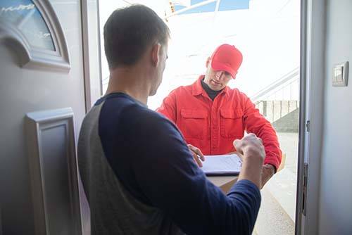 A man delivering a box of coffee to the door. This is at the top of a blog by Bean Merchant that explains where you can find the best coffee subscriptions in New Zealand in 2024.